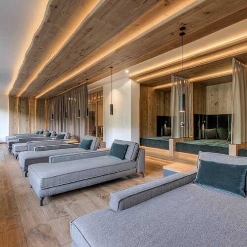 Ein eleganter Ruheraum mit modernen Liegen, sanfter Beleuchtung und Holzverkleidung, ideal für Entspannung und Erholung.