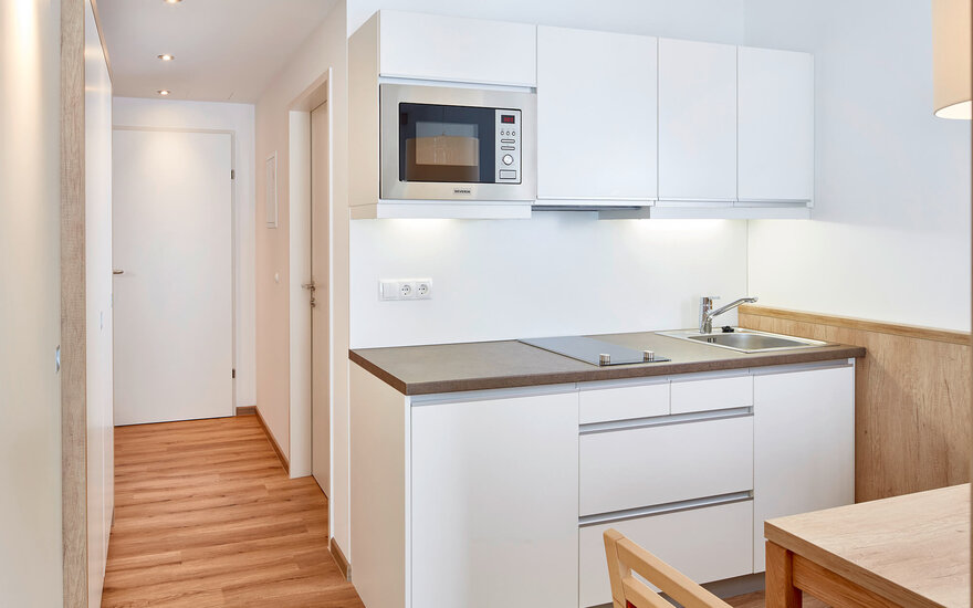 Ein Blick auf die funktionale Küche mit modernen Geräten, die durch die warmen Holztöne freundlich ergänzt wird.