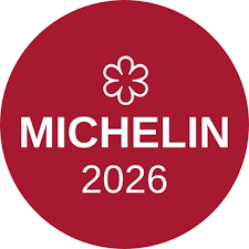 Ein rotes Logo mit dem Schriftzug 'MICHELIN' und der Jahreszahl 2026, umgeben von einem stilisierten Blumenmotiv.